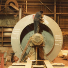 Worker placing labels on finished fan next to paint booth.